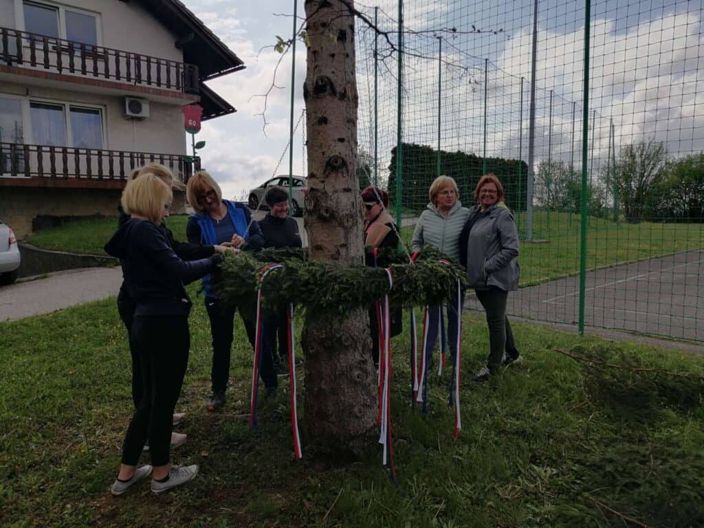 okraševanje mlaja, ženske okrašujejo mlaj z vencem in trakovi